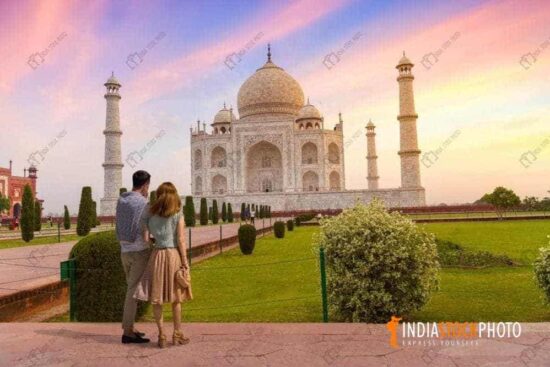 Tourist couple enjoy sunrise at historic Taj Mahal at Agra