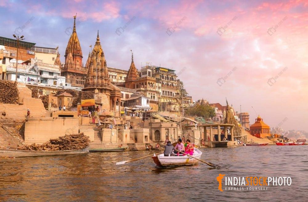 Varanasi ancient city architecture at sunset with tourist boat on river Ganges