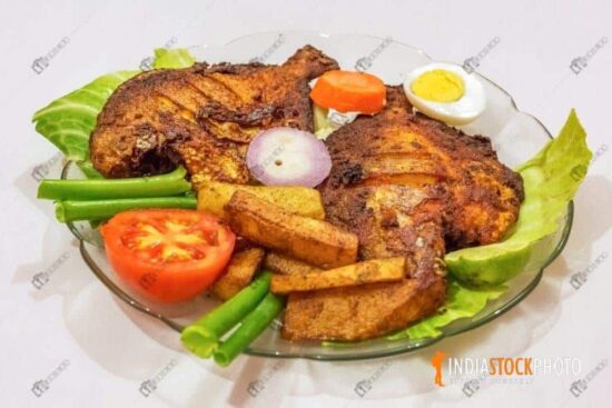 Crispy spicy fried pomfret fish with french fries and garnished with vegetables