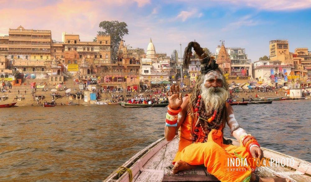Hindu sadhu on boat ride at Varanasi with view of ancient city architecture