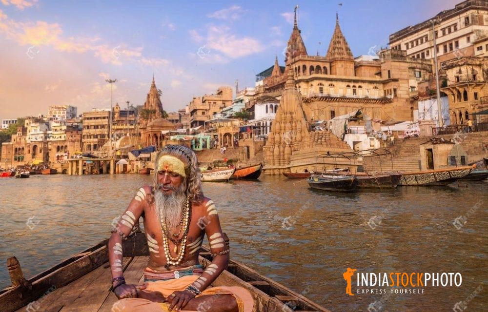 Indian sadhu on a boat at Varanasi with view of ancient city architecture