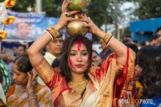 Married woman holding pitcher on her head as part of Durga Puja ritual