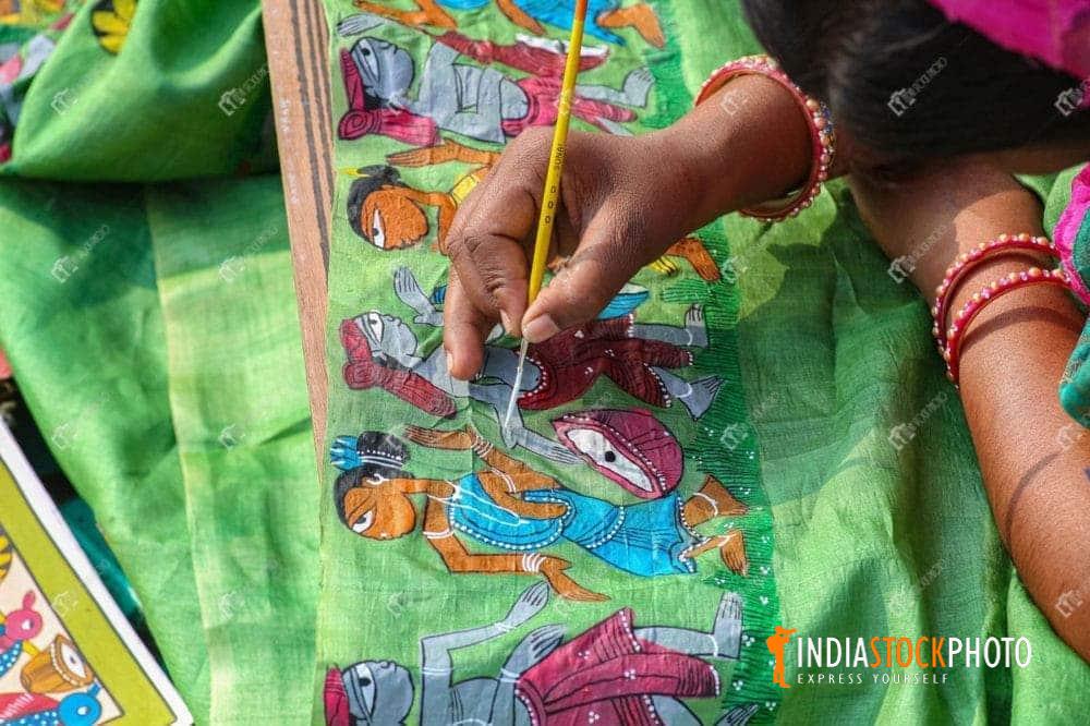 Woman artist hand doing fabric painting on women dress material