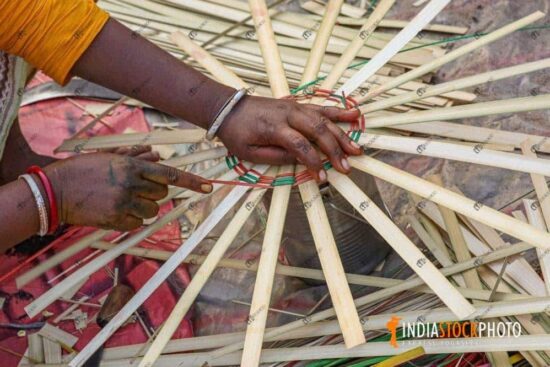 Hand of a rural woman weaving a basket with bamboo strands