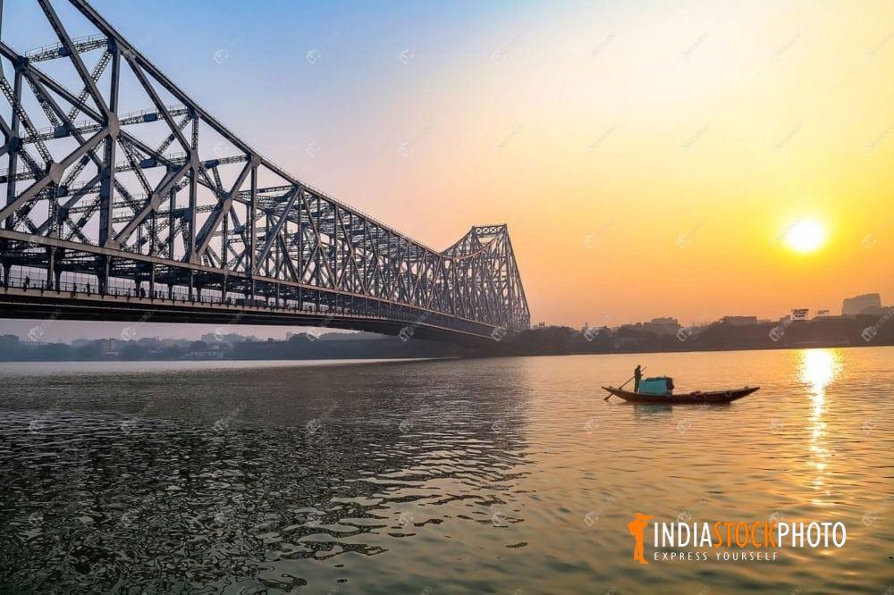 Howrah bridge Kolkata at sunrise with wooden boat on river Ganges
