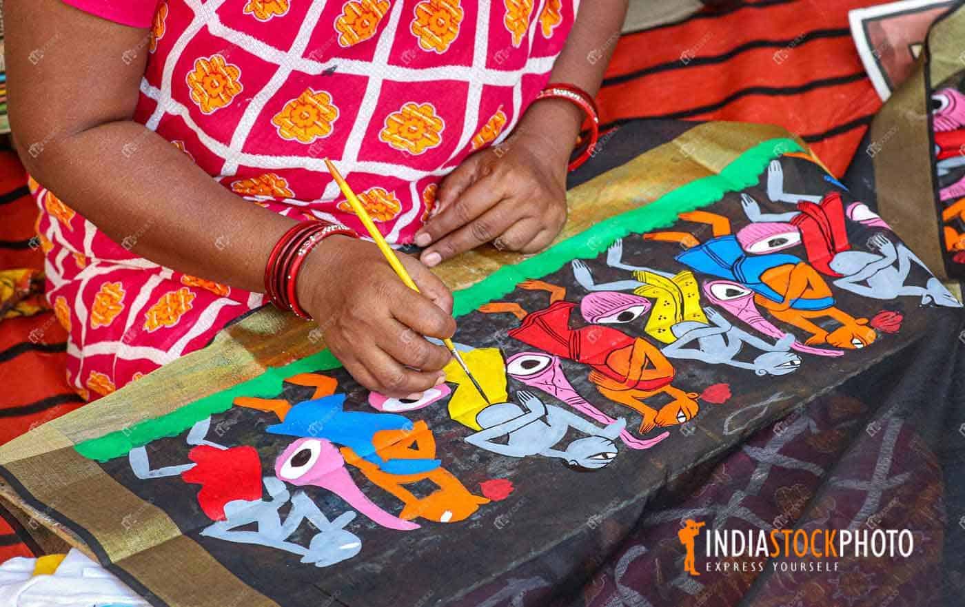 Local female artist doing fabric painting on women dress materials