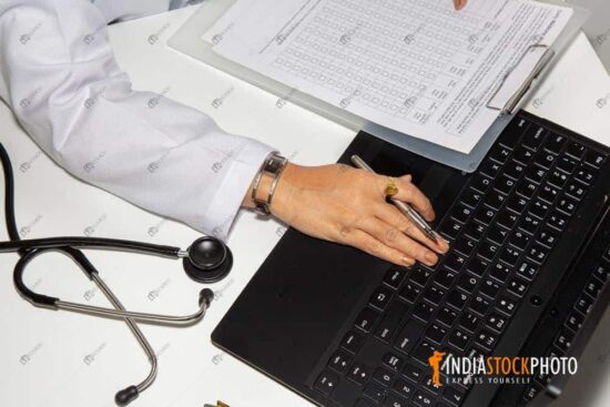 Indian doctor consulting her laptop while writing a prescription