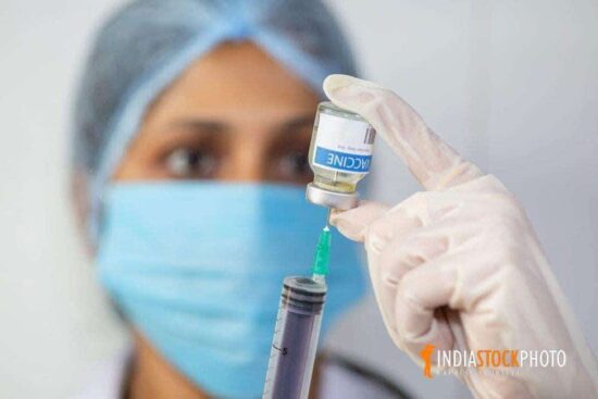Indian doctor draws vaccine into a syringe