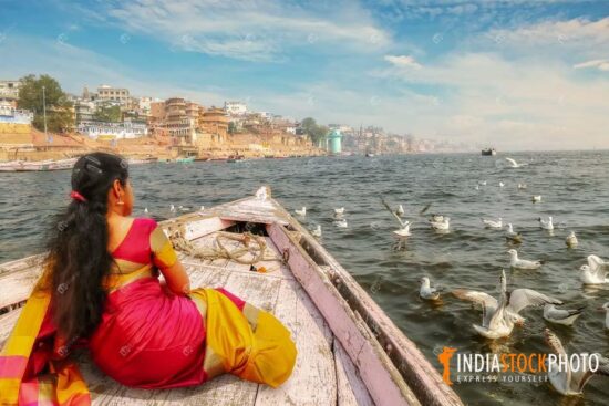 Woman enjoy Ganges boat ride at Varanasi with view of migratory birds