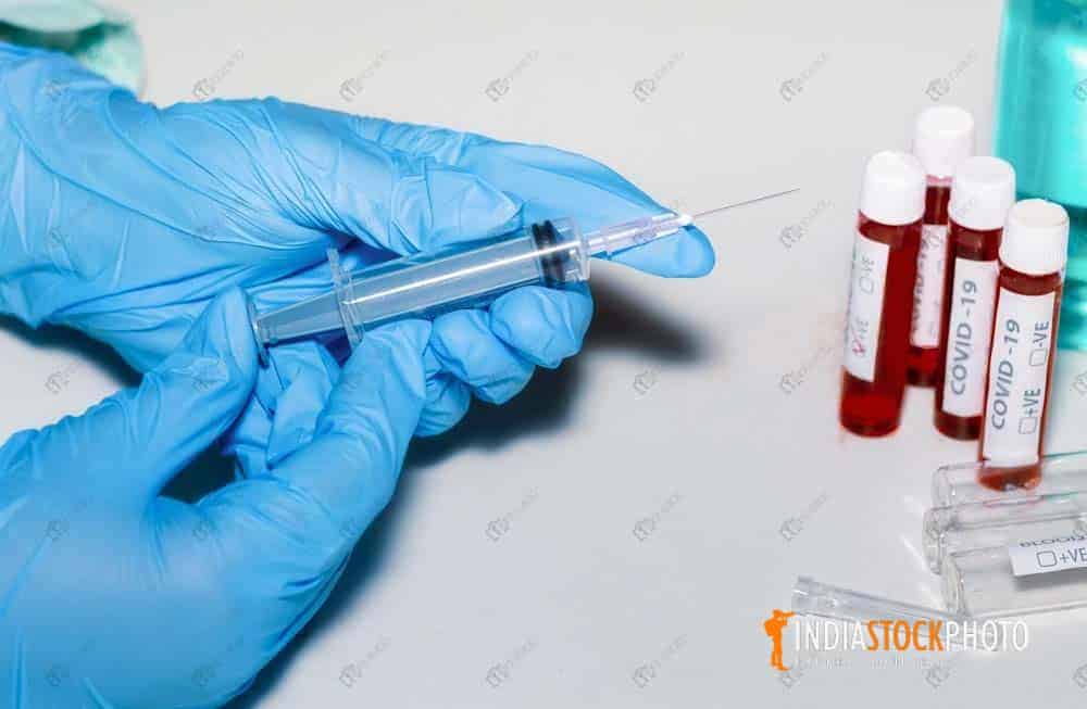 Nurse holds injection syringe with blood sample vials