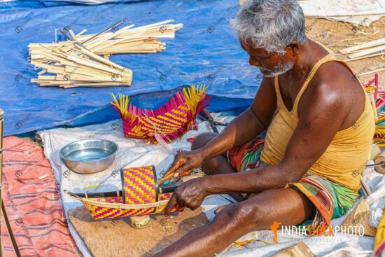 Old man making a handicraft item with bamboo canes