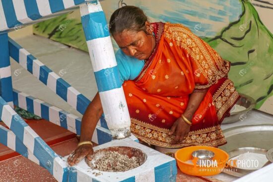Rural woman grinding rice with manual grinder