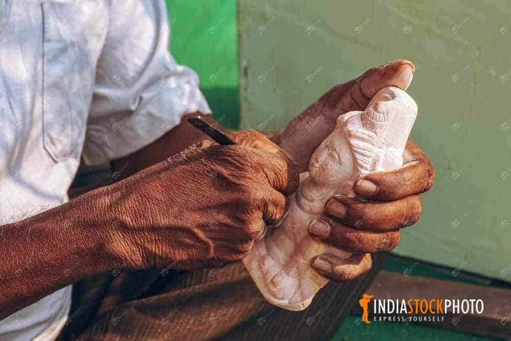 Artist hand working on a miniature sculpture of Indian deity