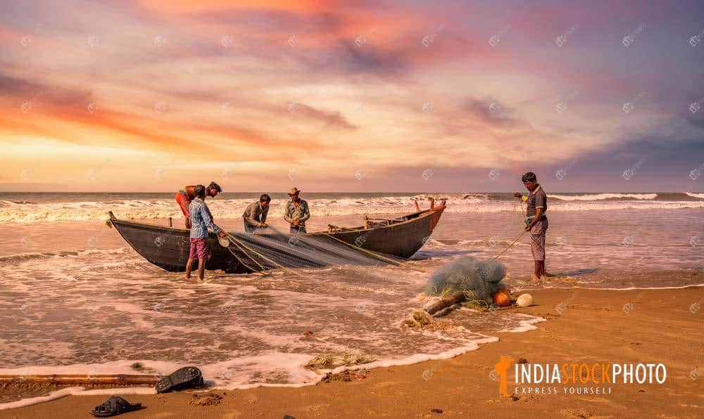 Fishermen return to shore at Orissa sea beach at sunset