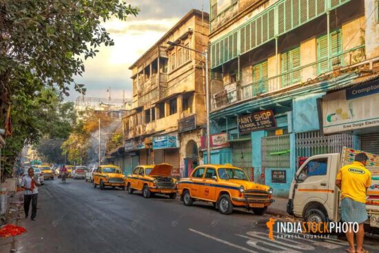 Old residential buildings with yellow cabs at Kolkata city lane
