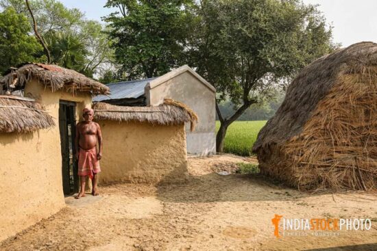 Rural man standing at the doorstep of his mud hut at an Indian village